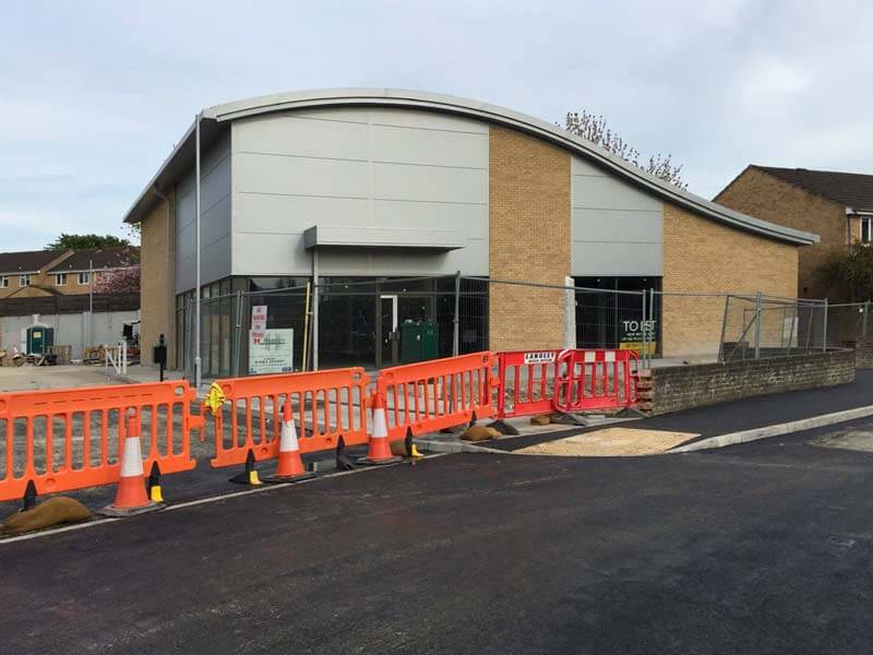 New build modern commercial construction amongst building site with modern sloped roof.